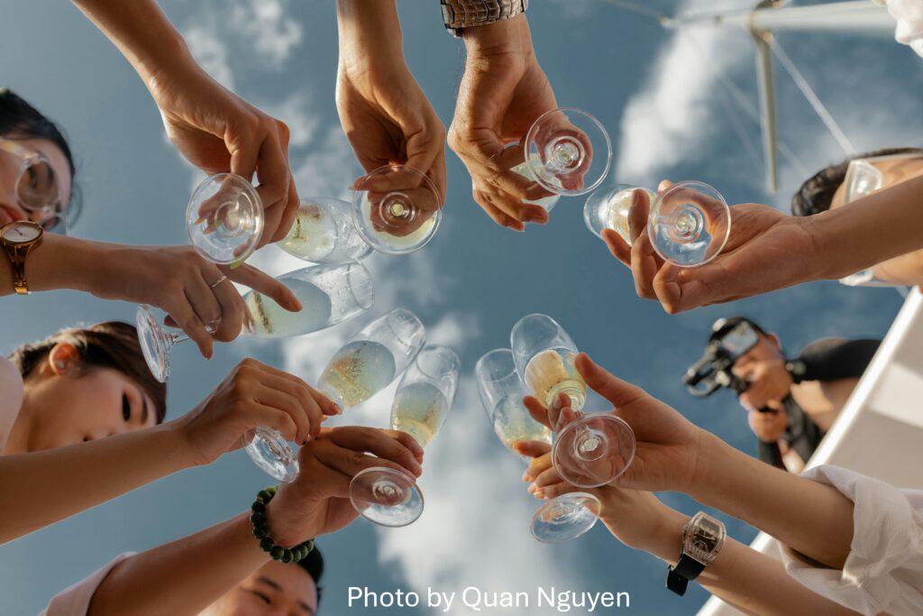 Friends bachelorette party on a sailboat, bringing glasses together for a toast