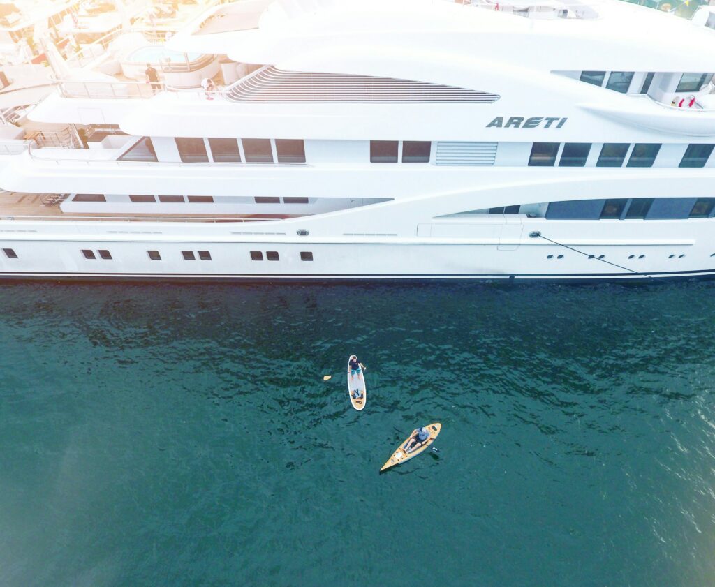 super yacht with guest on a paddle board next to it